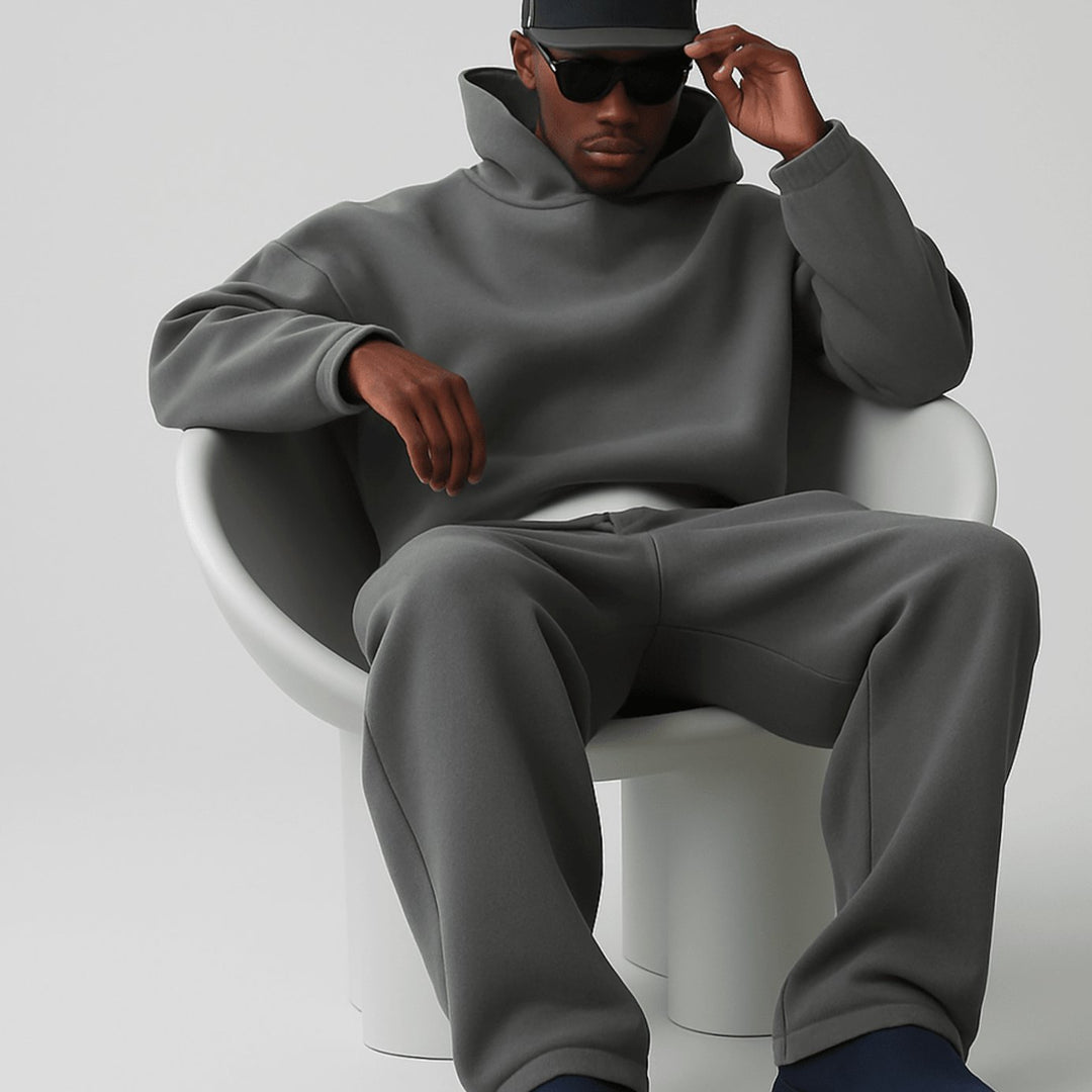 Man sitting in a dark grey oversized hoodie and jogger set