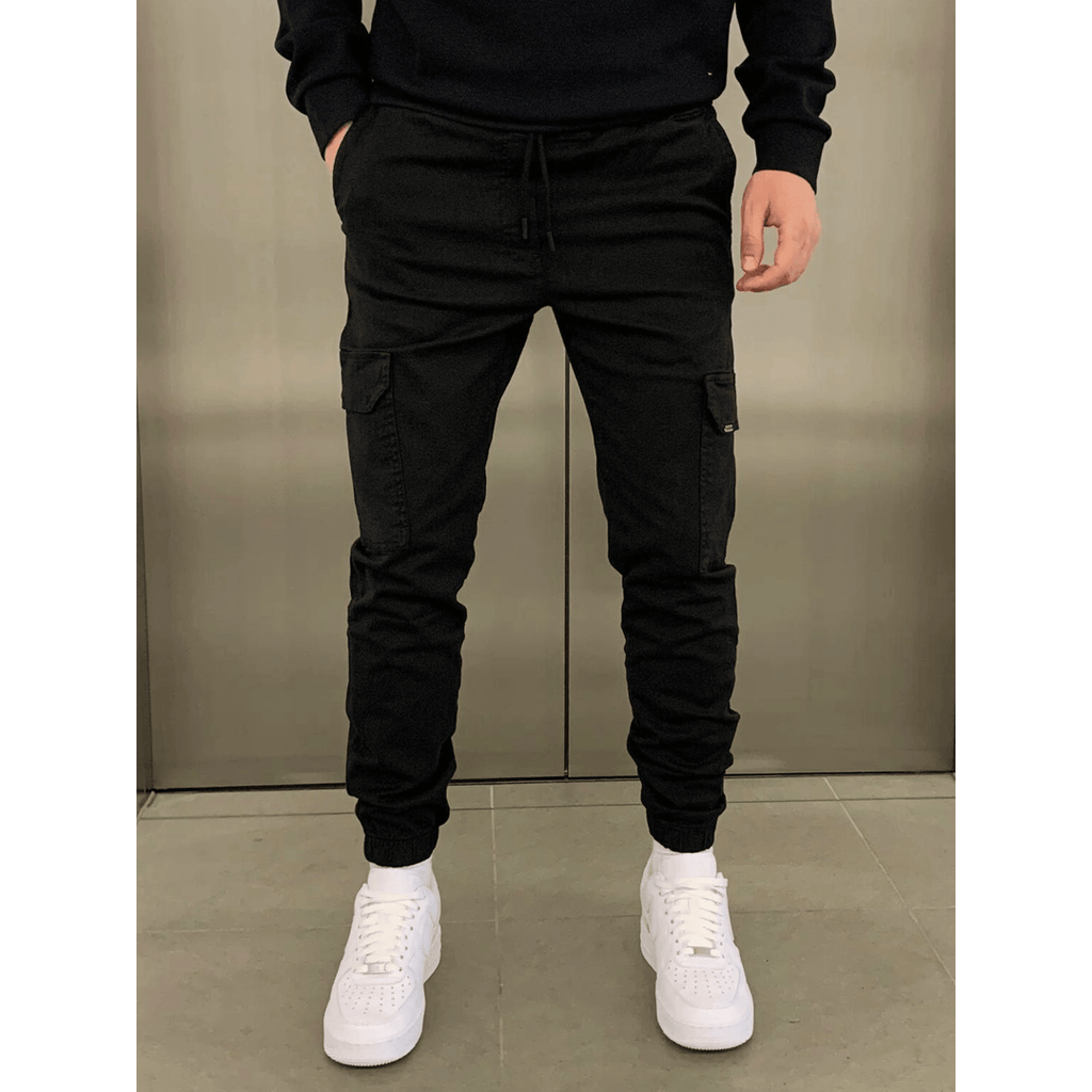 Man wearing black slim cargo joggers with white trainers