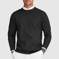 Man wearing a black crew neck knit sweater over a shirt