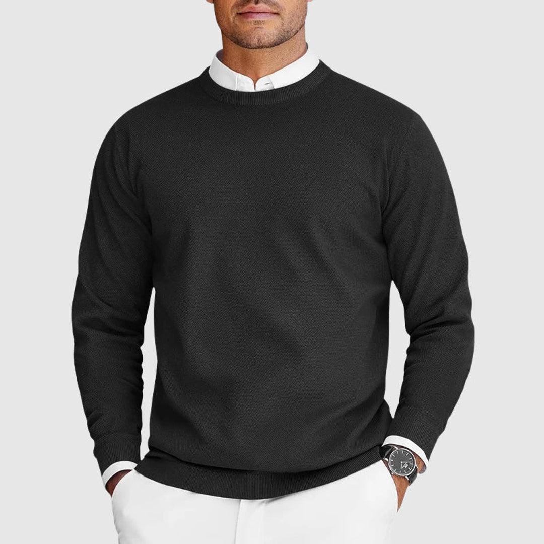 Man wearing a black crew neck knit sweater over a shirt