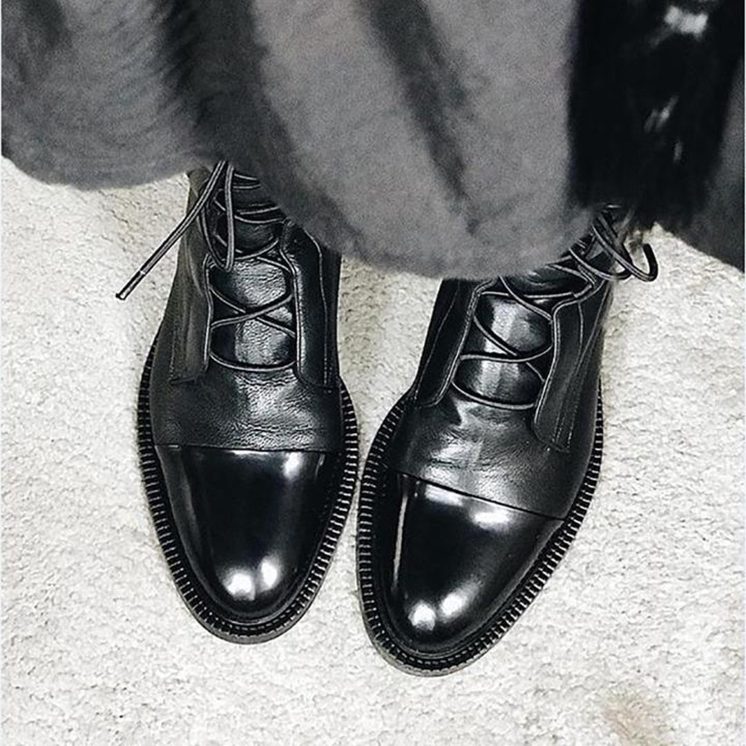 Close-up of black lace-up boots with grey coat