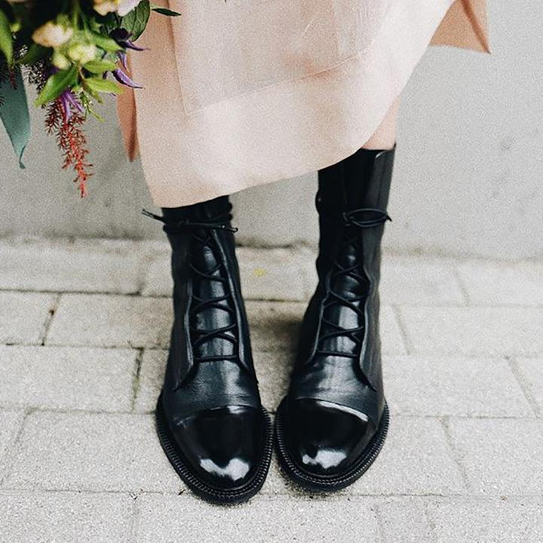 Woman wearing black lace-up boots with a light dress
