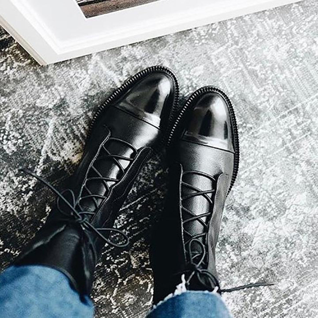 Black lace-up ankle boots on stone paving