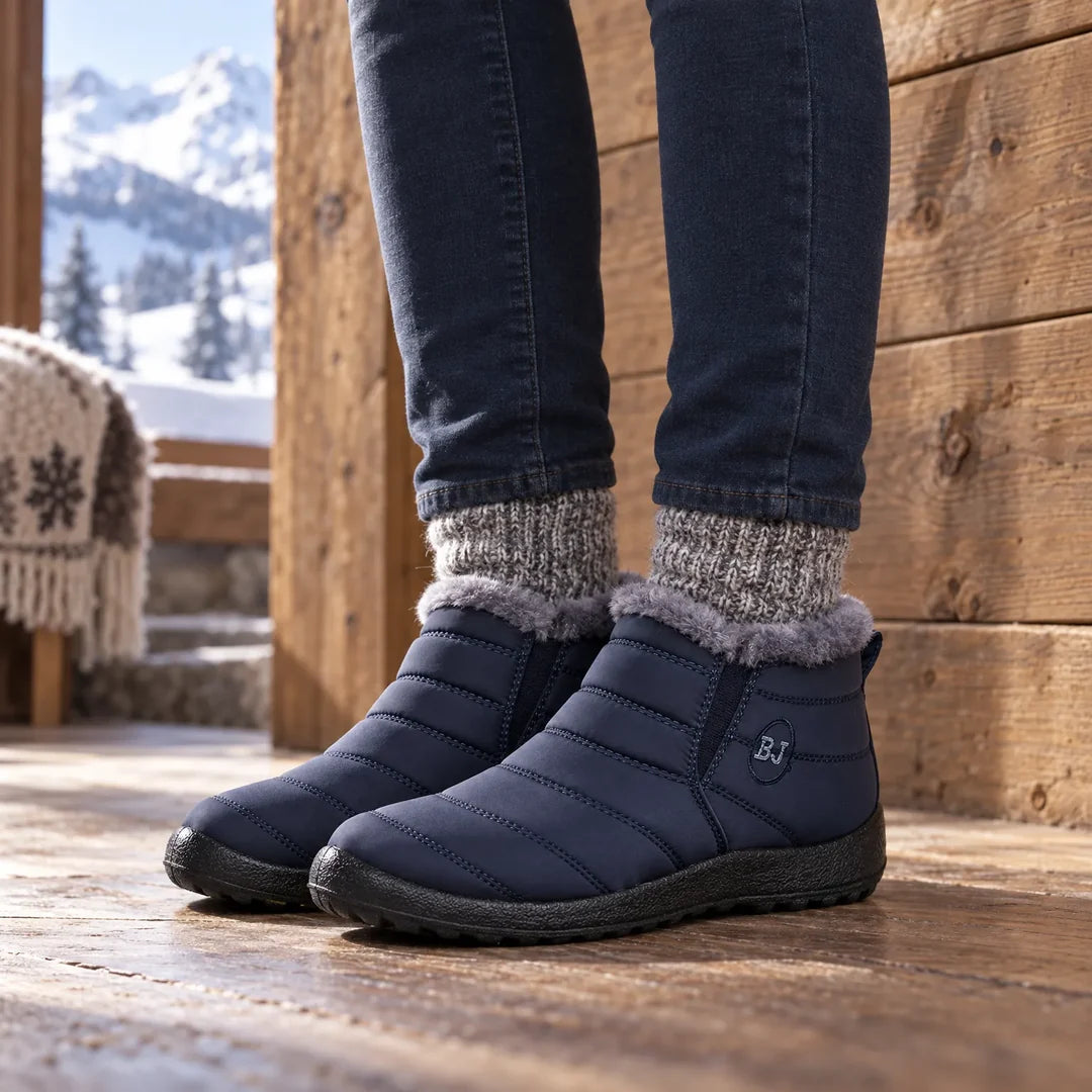 Woman wearing navy quilted ankle boots by a window