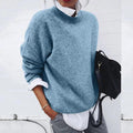 Woman wearing a blue relaxed knit sweater over a white shirt