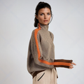 Woman wearing a taupe turtleneck with orange sleeve stripes