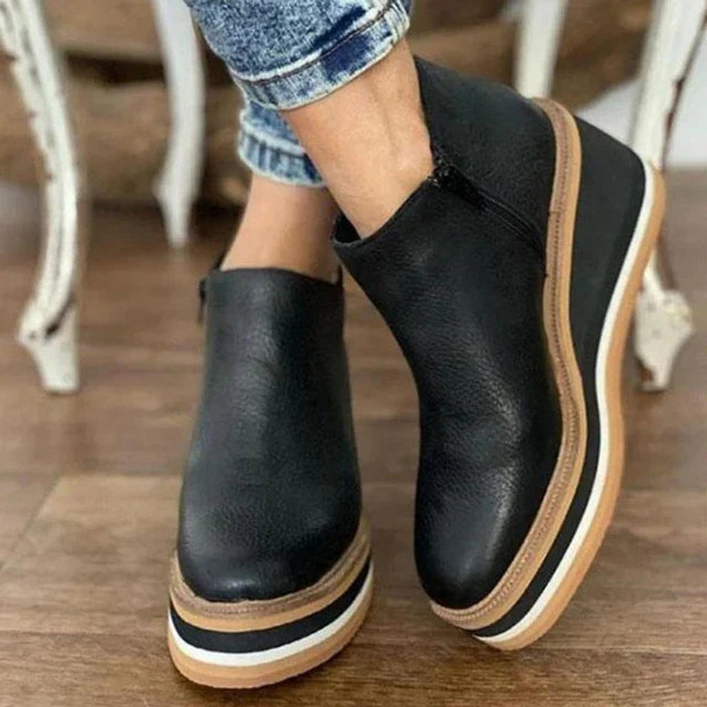Woman wearing black wedge platform ankle boots