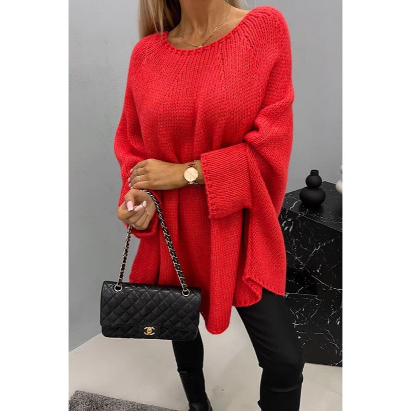 Red knit poncho sweater with black trousers