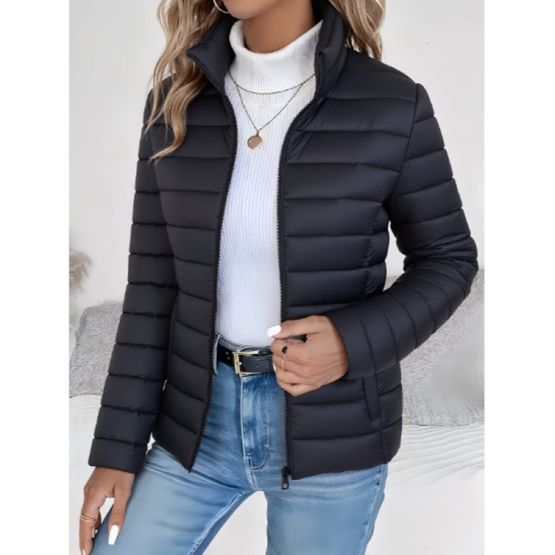 Black lightweight quilted jacket with stand collar over a white roll-neck